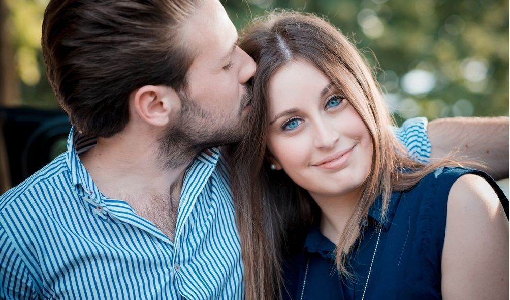 Homem beijando a cabeça de mulher