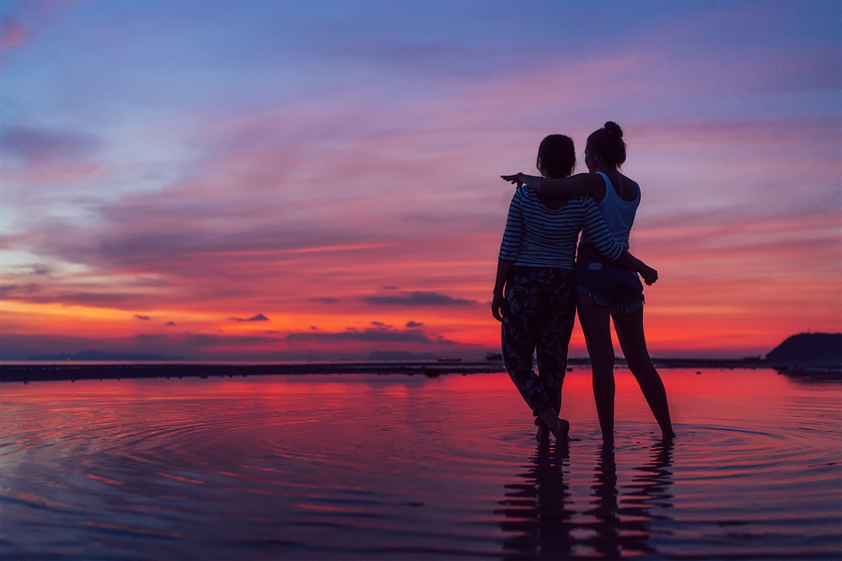 Amigas caminhando no pôr do sol rosa