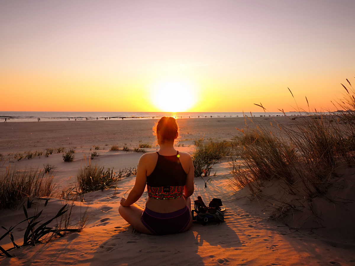 Mulher meditando durante o pôr do sol