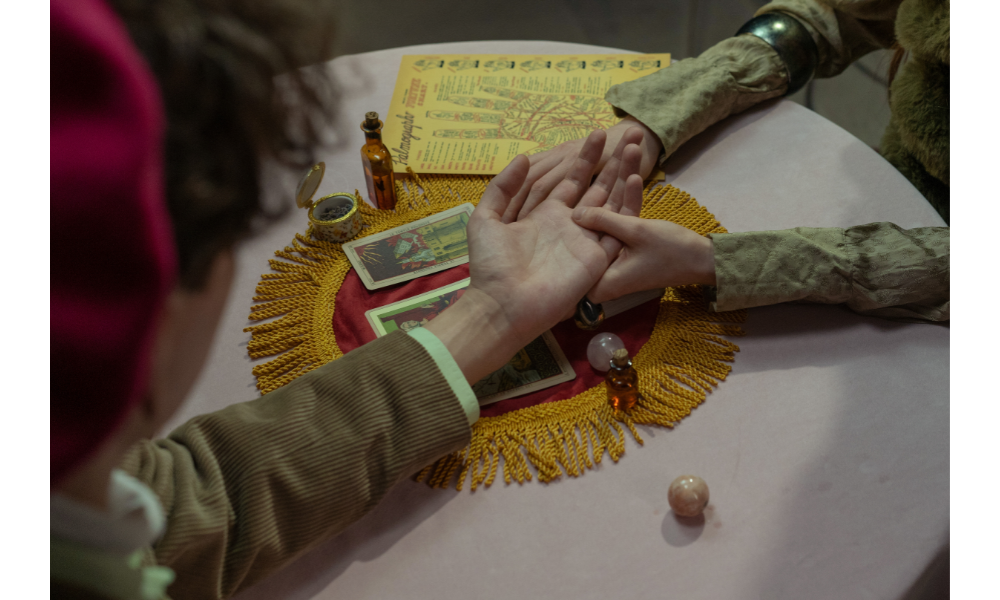 Quiromancia - leitura de mãos sobre uma mesa ao lado de cartas.