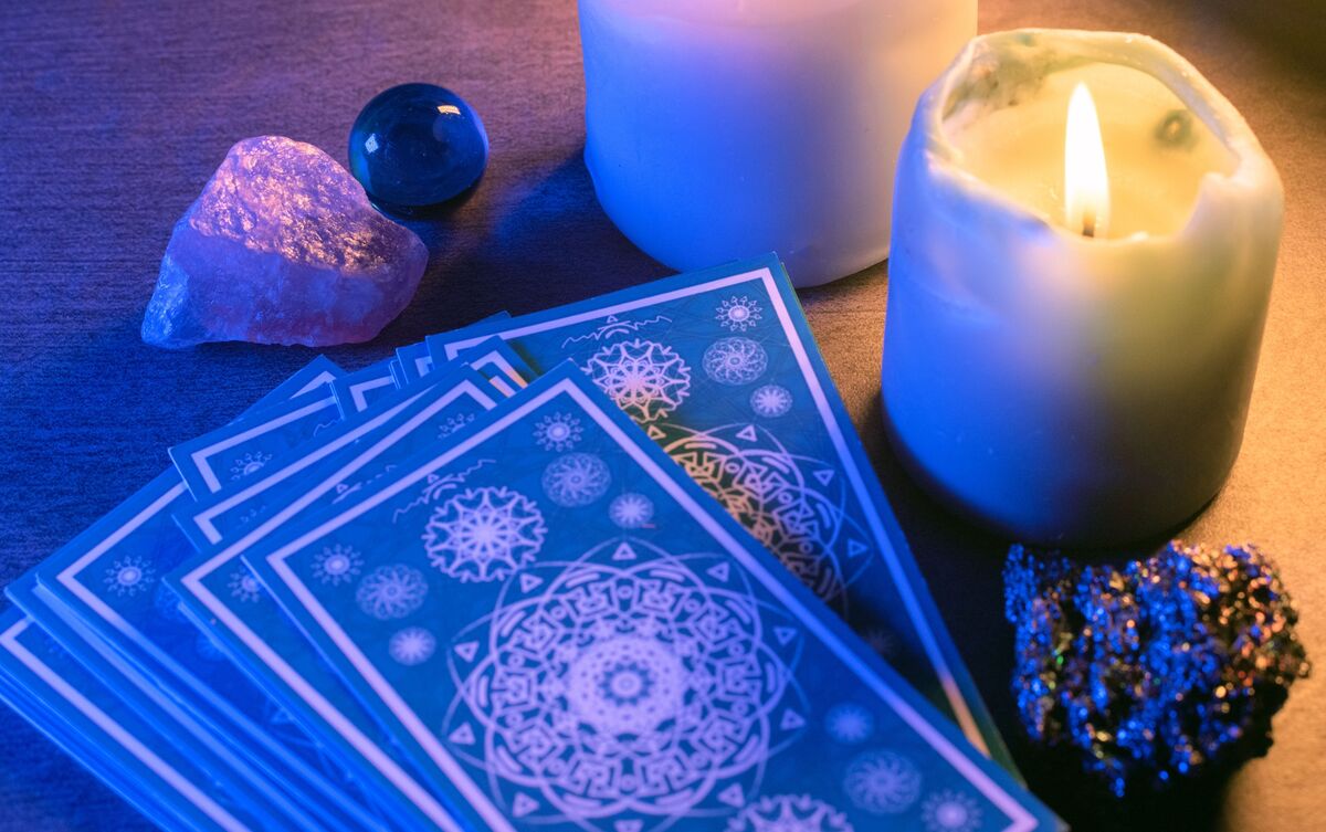 Cartas de Tarot empilhadas com velas ao lado.