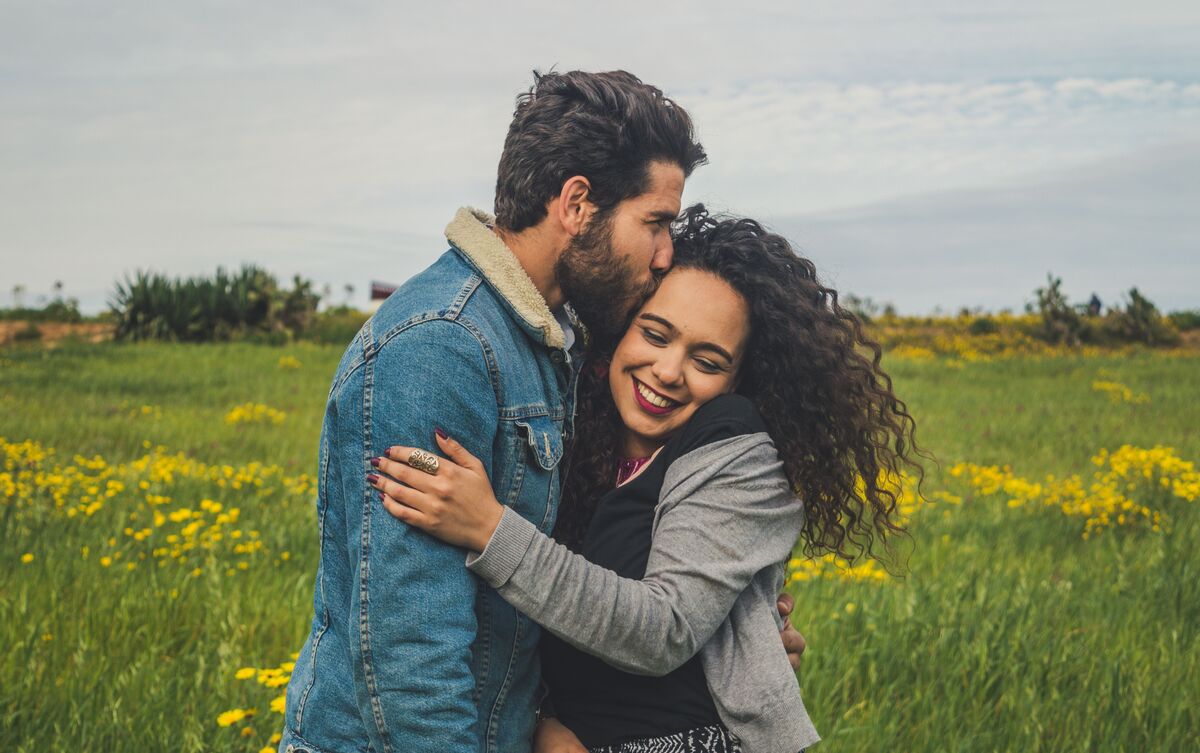 Casal de homem e mulher abraçados ao ar livre.