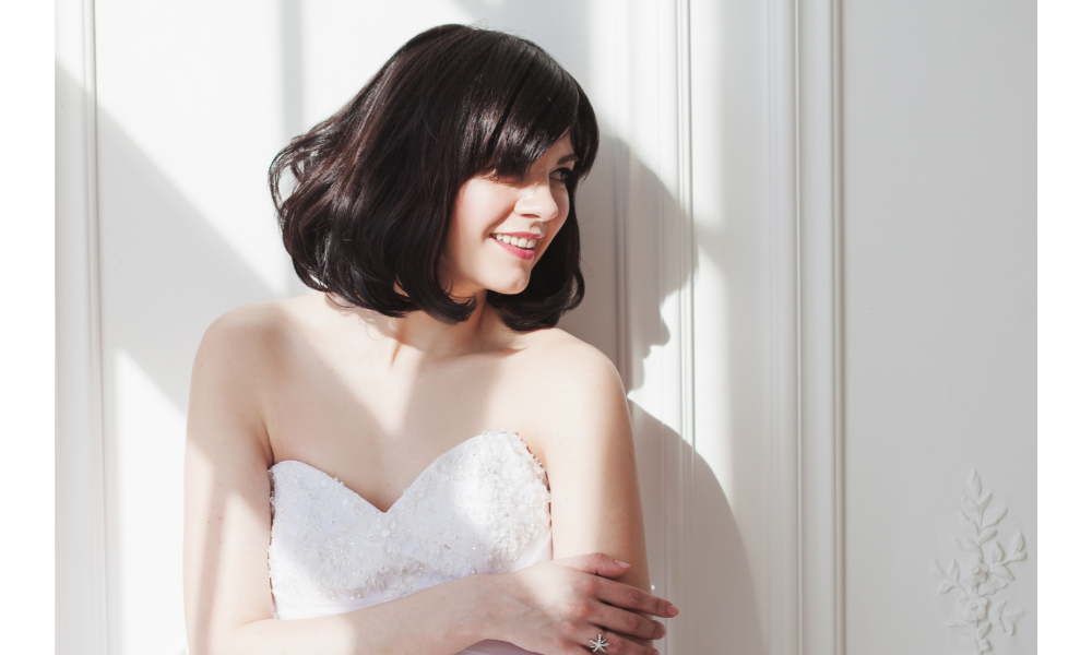 Mulher, de cabelo preto curto e vestido de noiva, sorrindo.