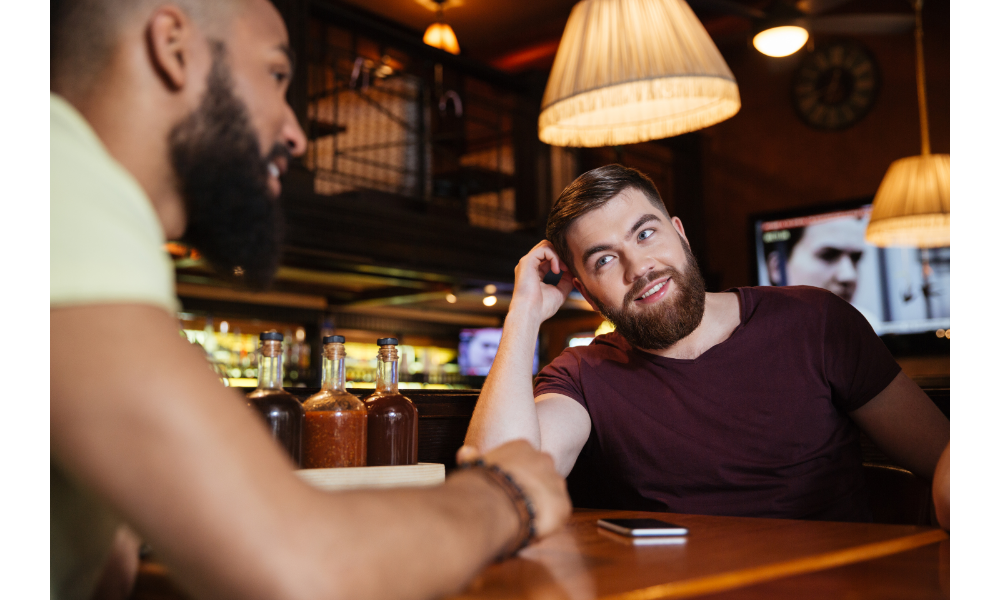 Casal de homens em um bar se olhando.