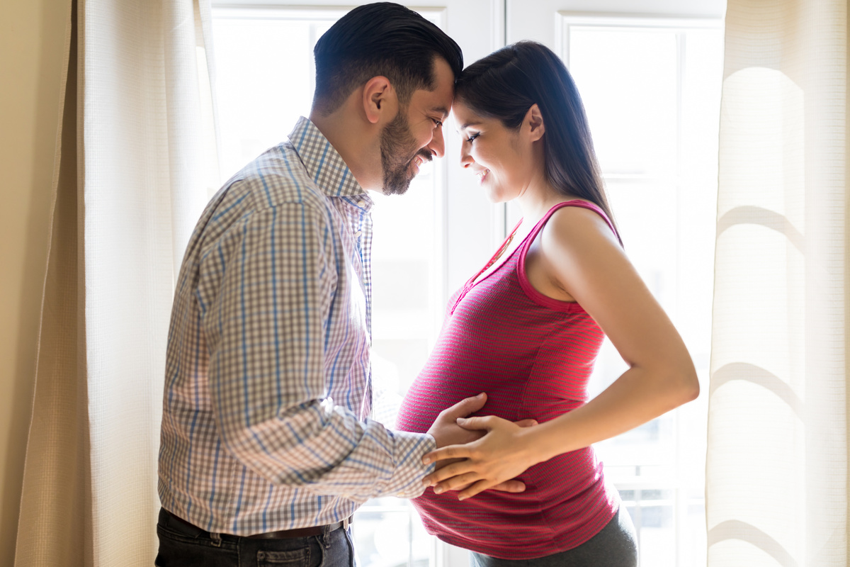 Um homem com as mãos na barriga de uma mulher grávida