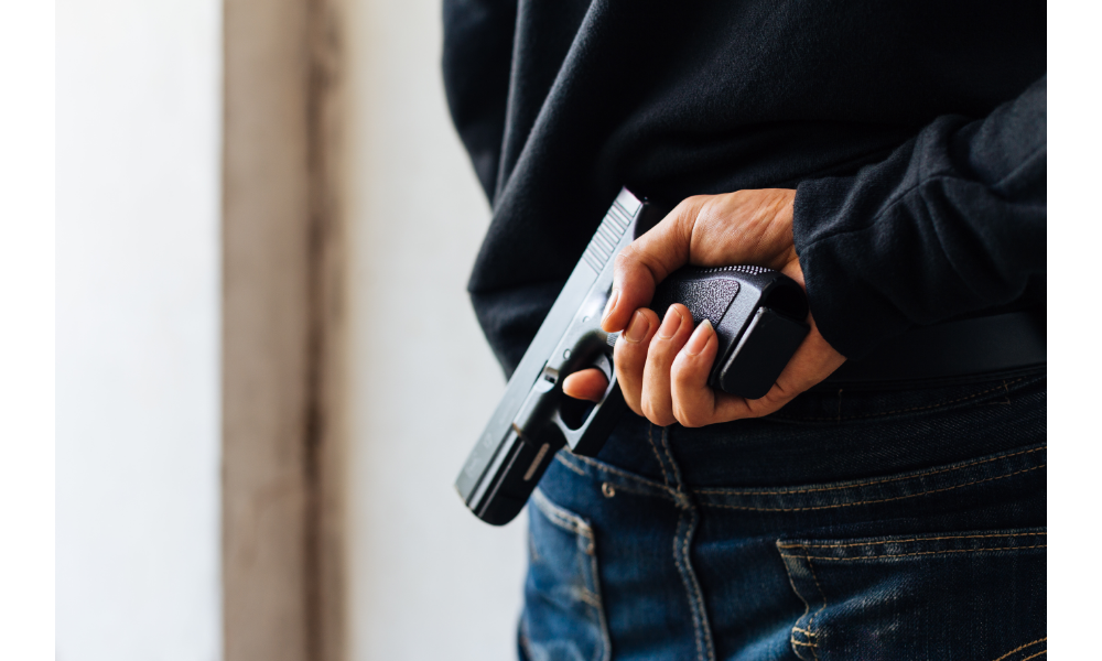 Homem de costas segurando uma arma.