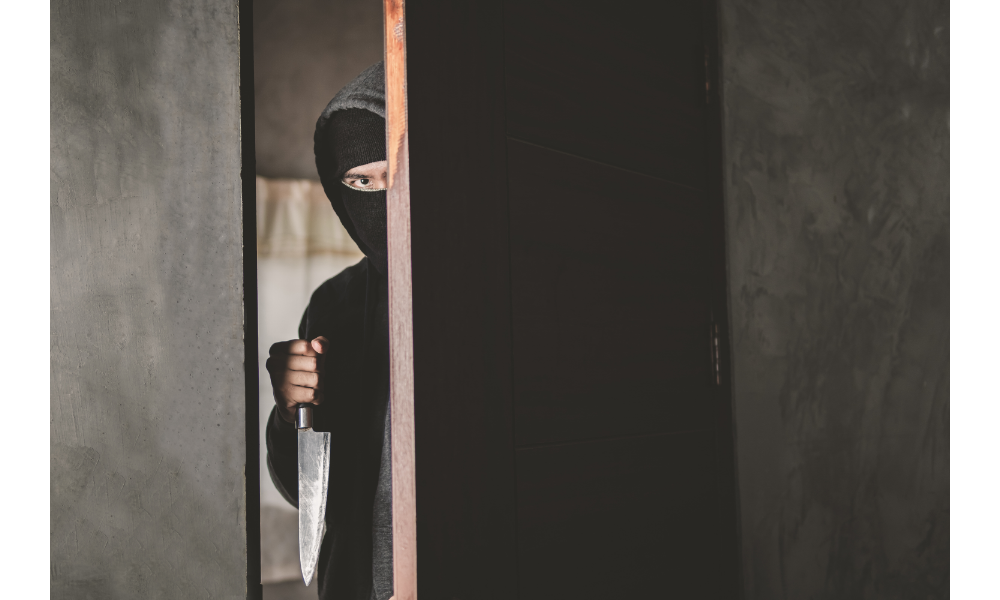 Homem entrando por uma porta com faca na mão.