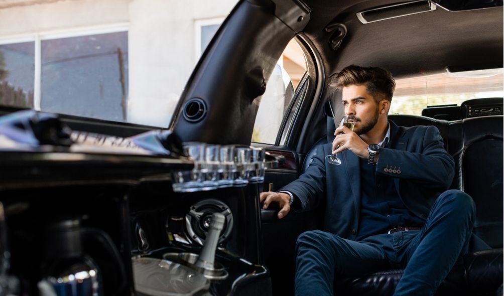 Homem tomando uma taça de Champagne dentro de uma limousine