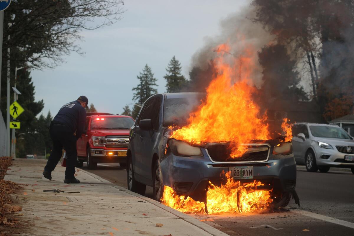 Carro pegando fogo na rua.