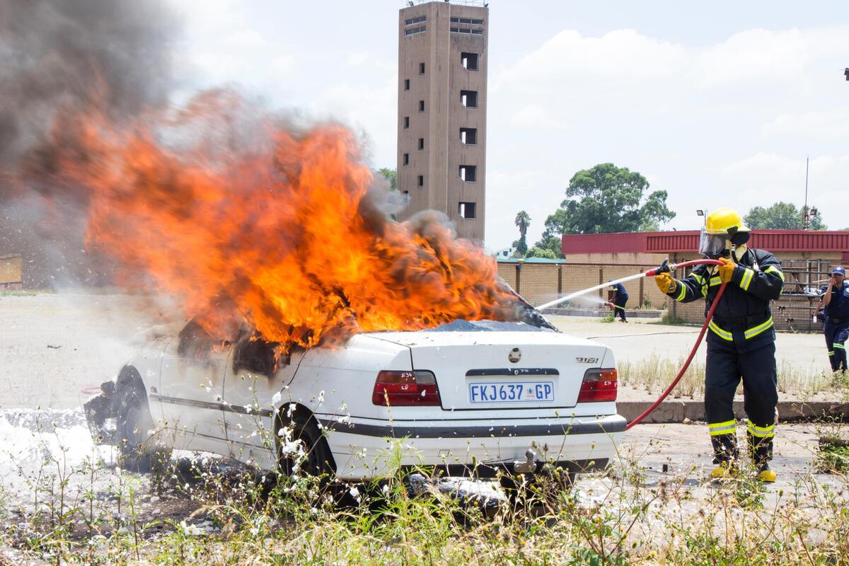 Bombeiro apagando carro pegando fogo.