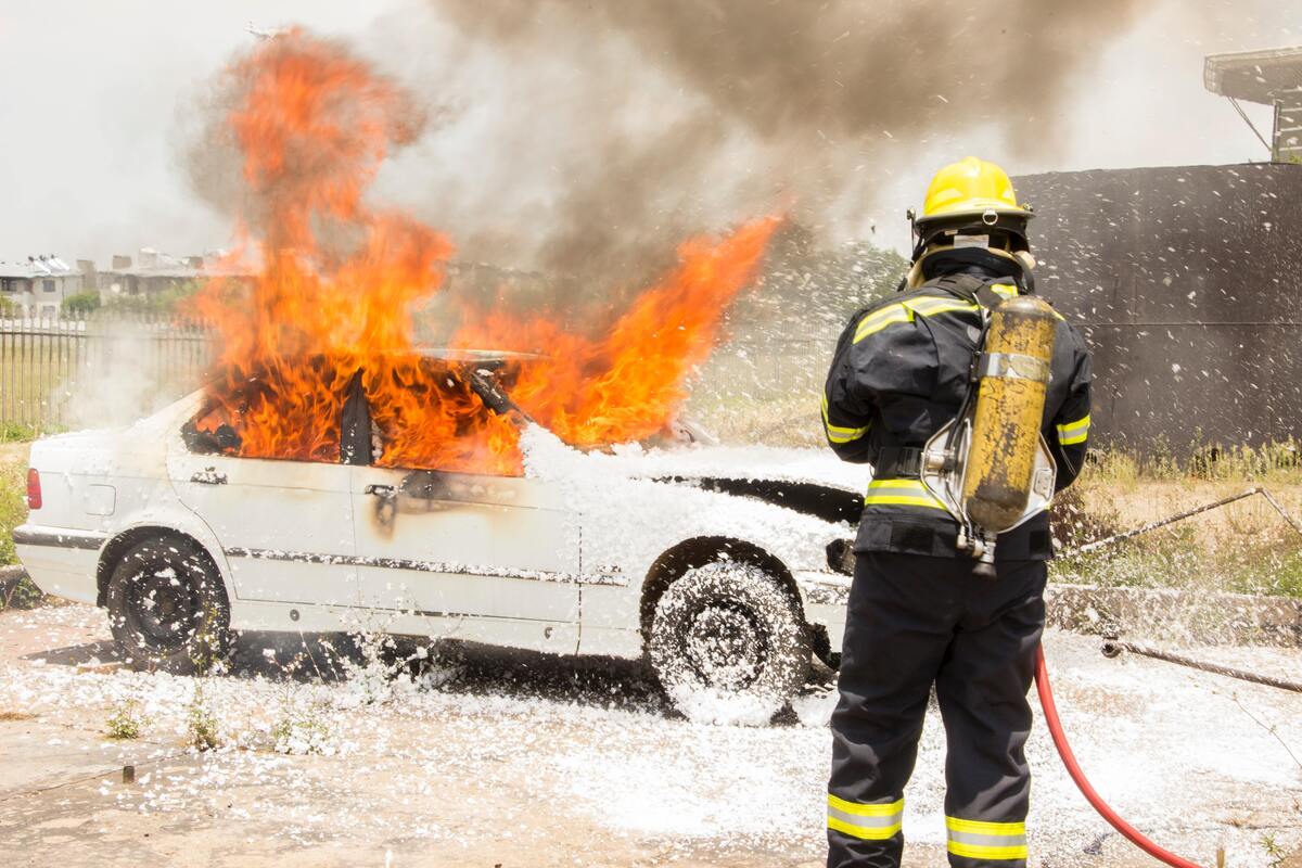 Bombeiro apagando carro pegando fogo.