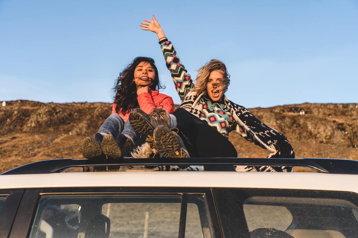 Duas mulheres em cima de um carro.