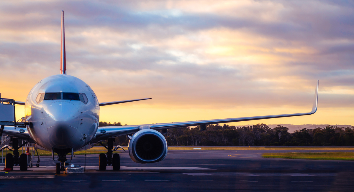 Avião manobrando na pista durante o entardecer.