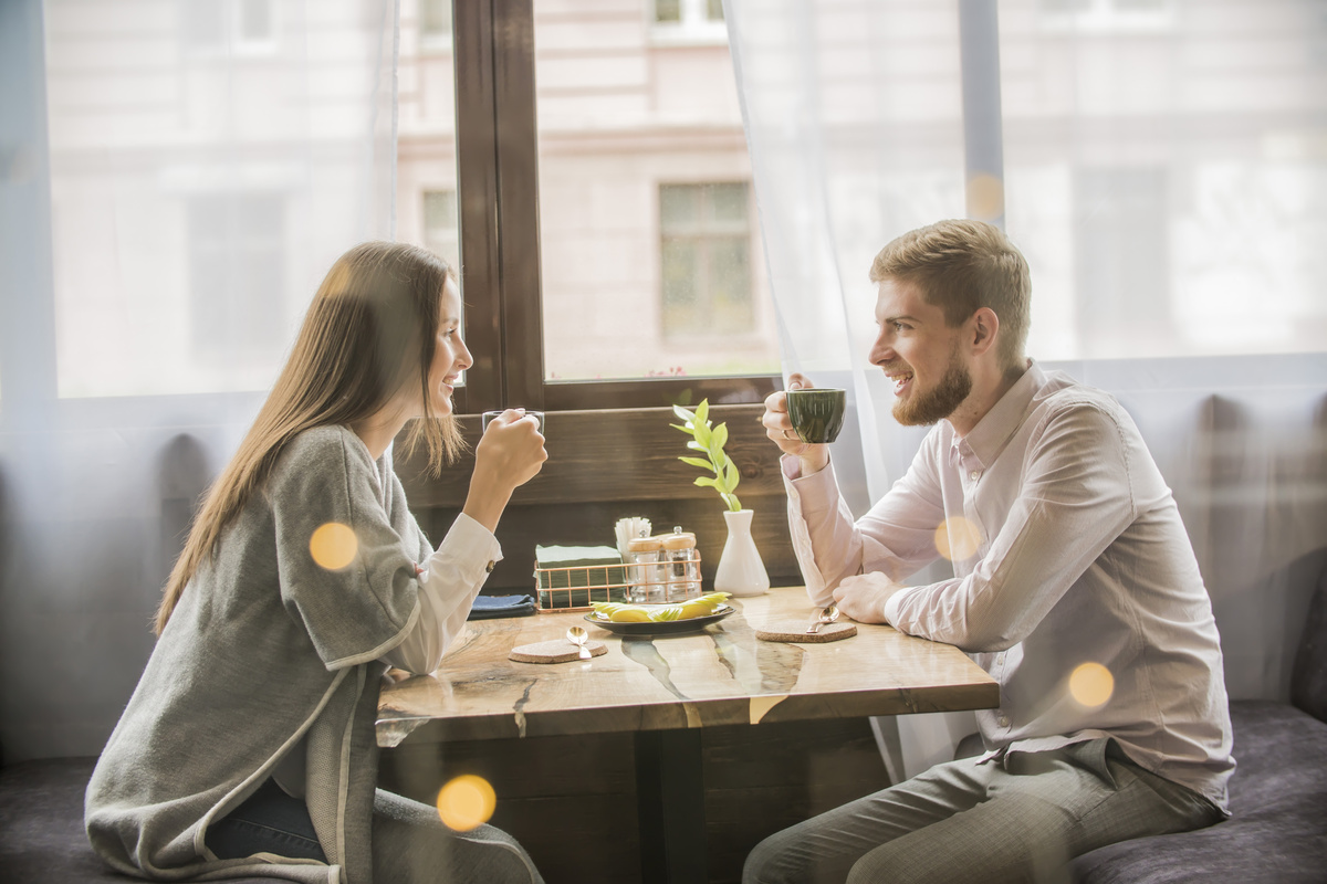 Casal sorridente tomando café enquanto conversam