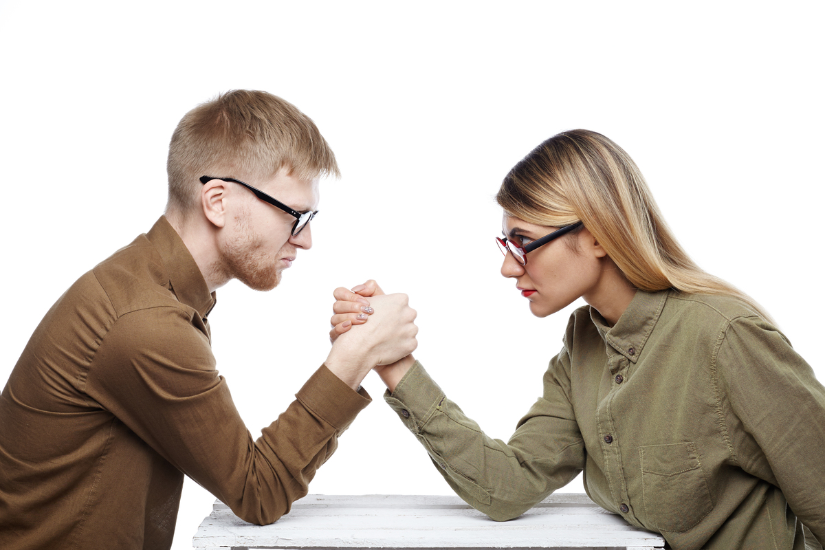 Homem e mulher em uma queda de braço.