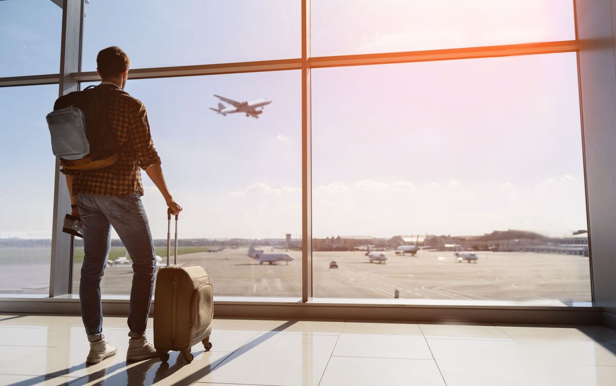 Homem com malas observando avião.