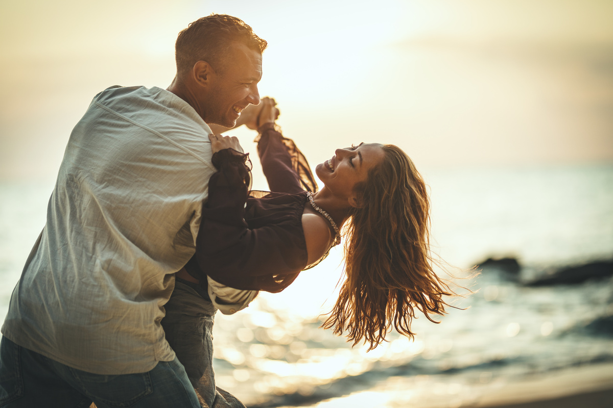 Casal dançando feliz na praia.