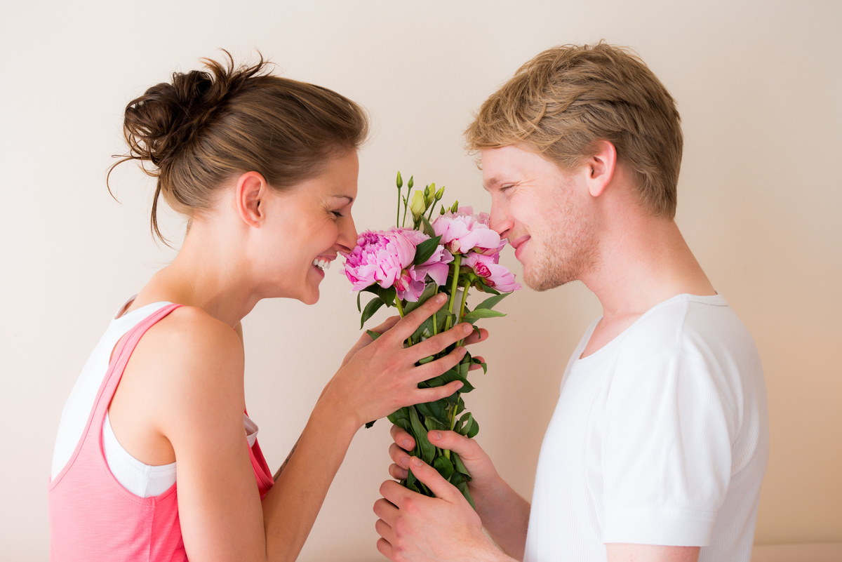 Homem entregando buquê de flores para mulher ao fazer pedido de namoro.