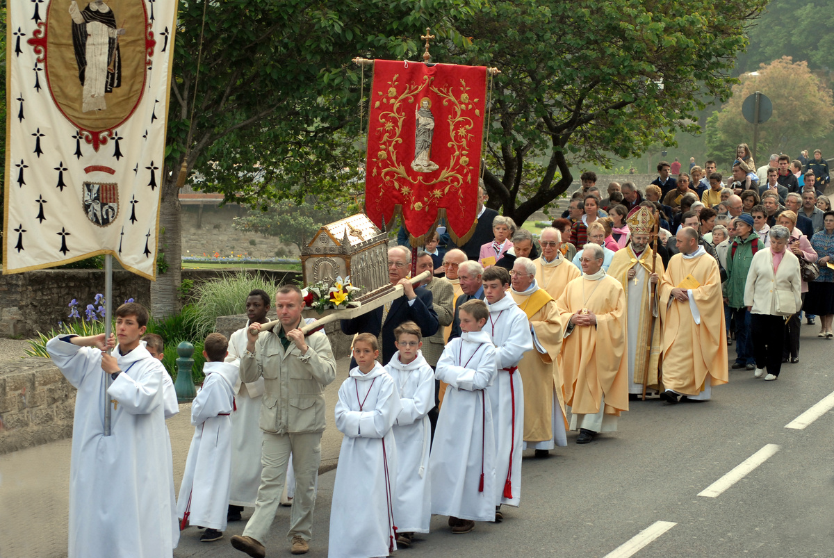 Procissão católica com padre e imagem de Santo.