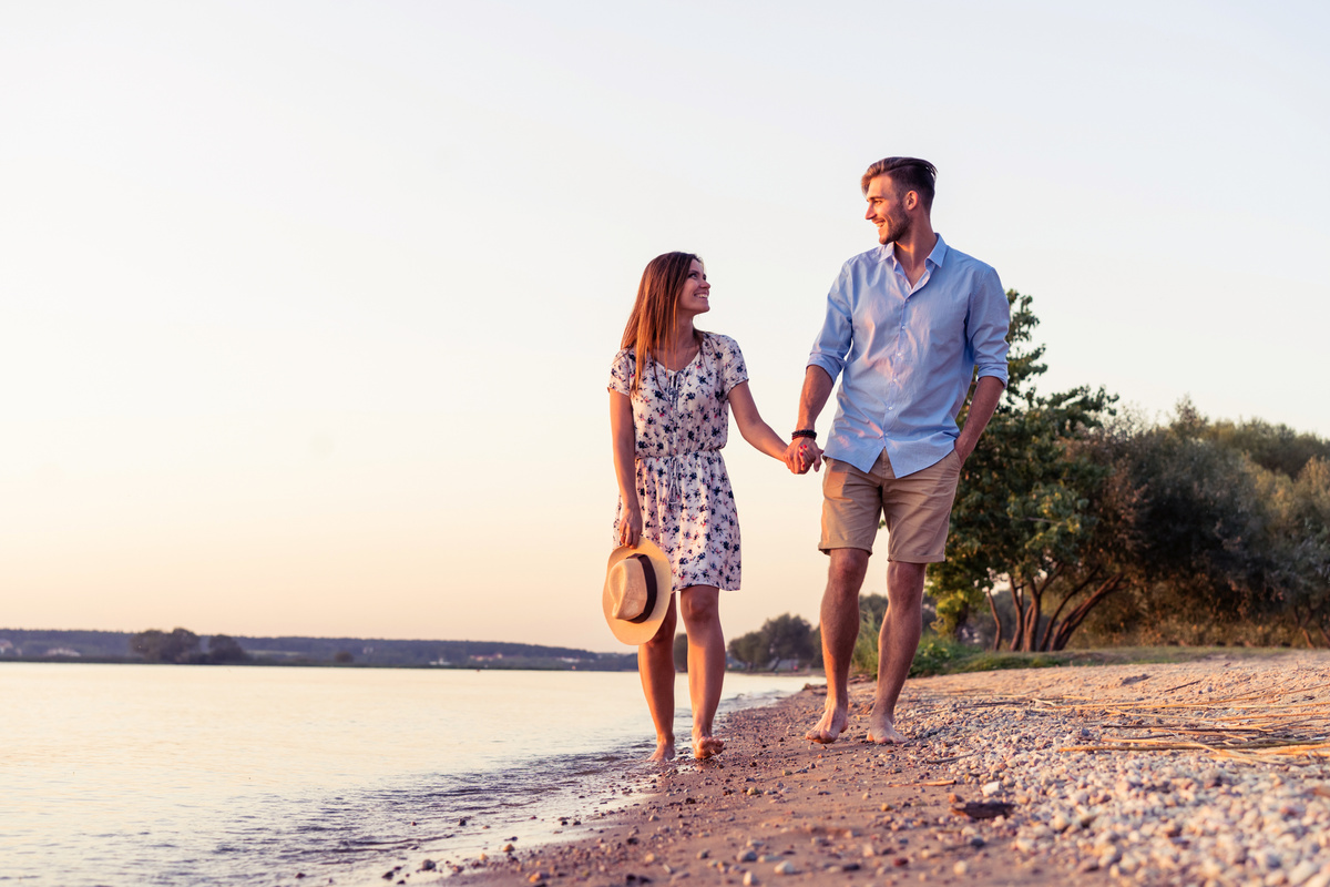 Um homem e uma mulher caminhando descalços e de mãos dadas