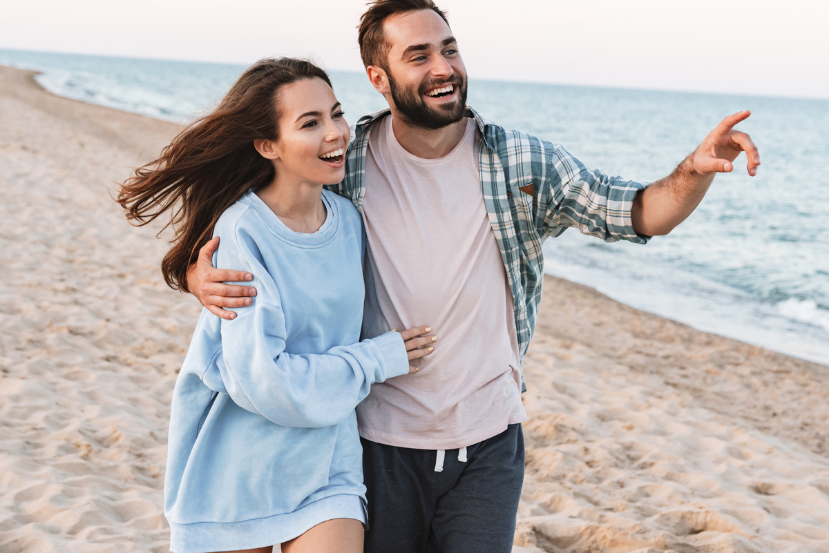 Um homem e uma mulher caminhando abraçados na praia