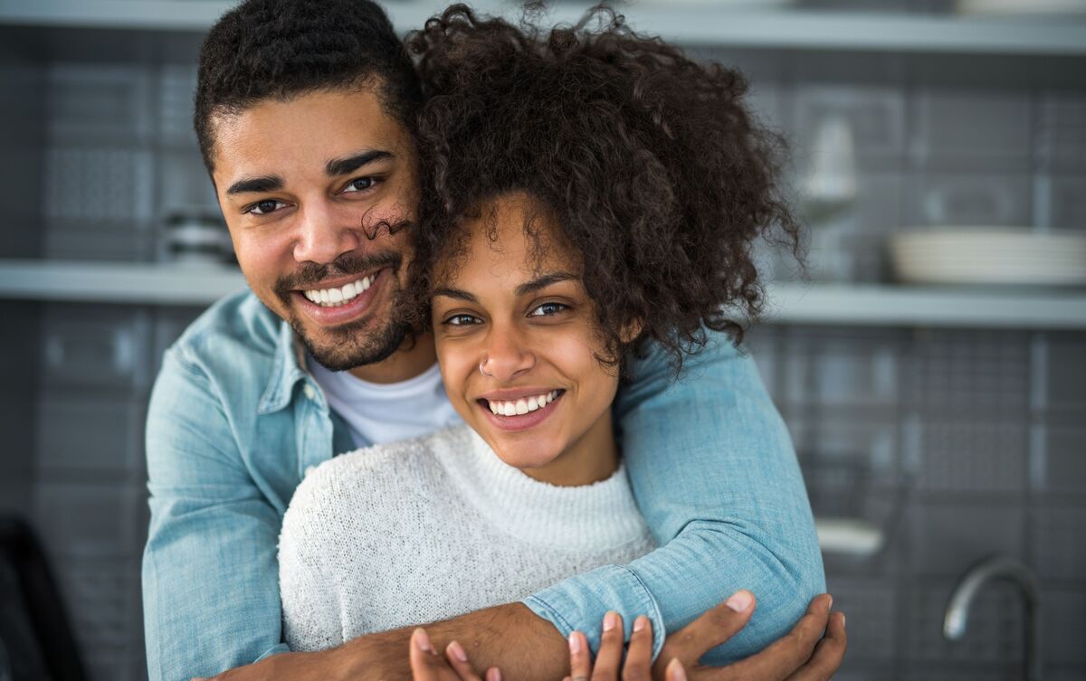 Casal de homem e mulher abraçados e felizes.