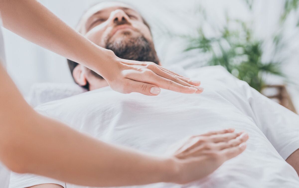 Mulher aplicando técnica de Reiki em cliente.