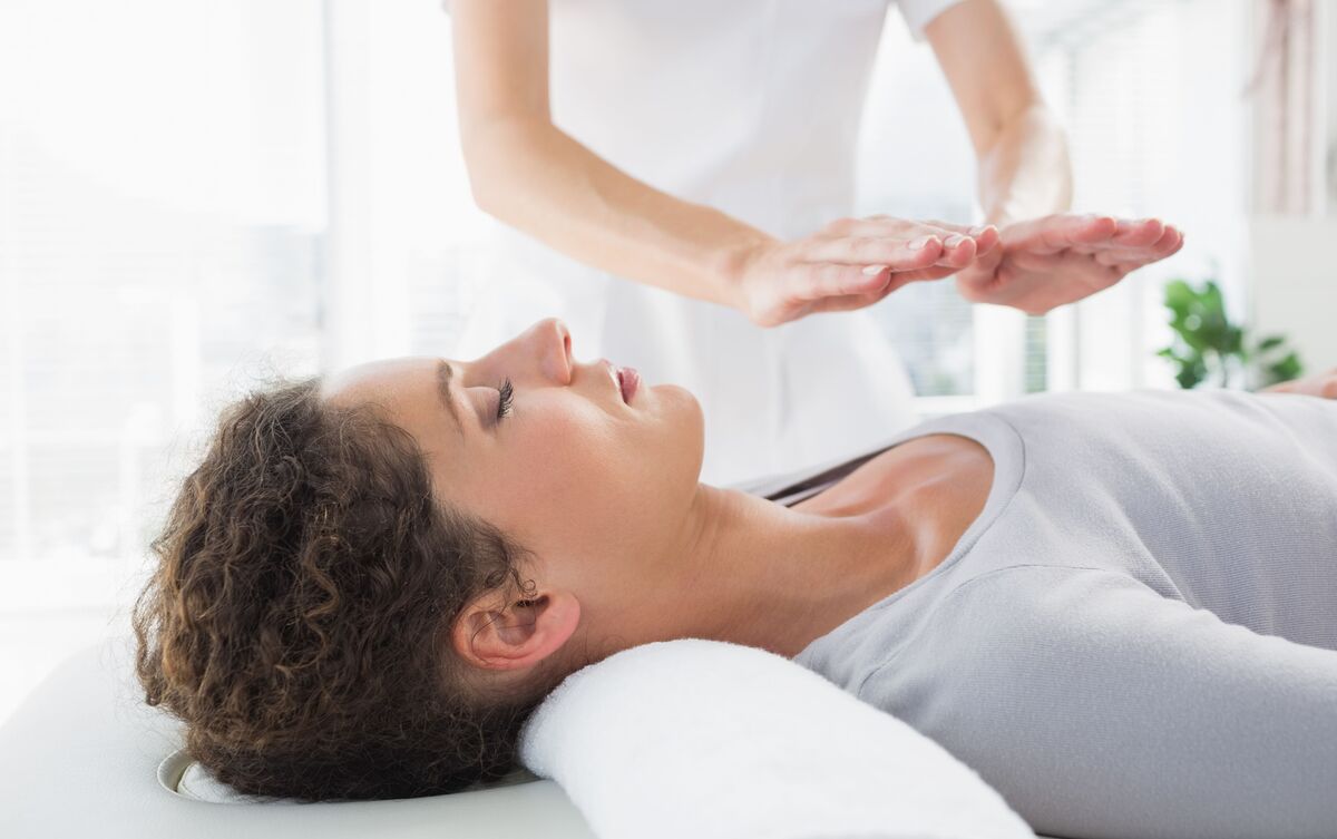 Mulher aplicando técnica de Reiki em cliente.