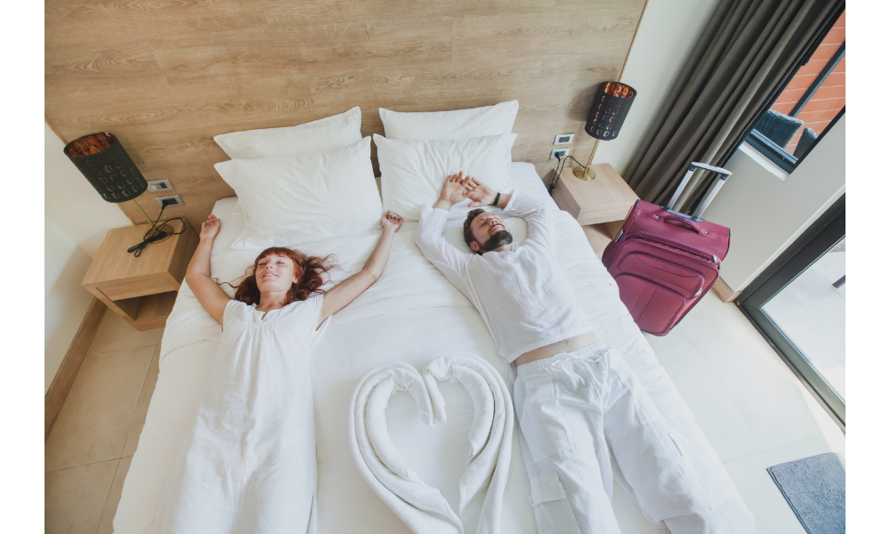 Casal deitado em uma cama de hotel.