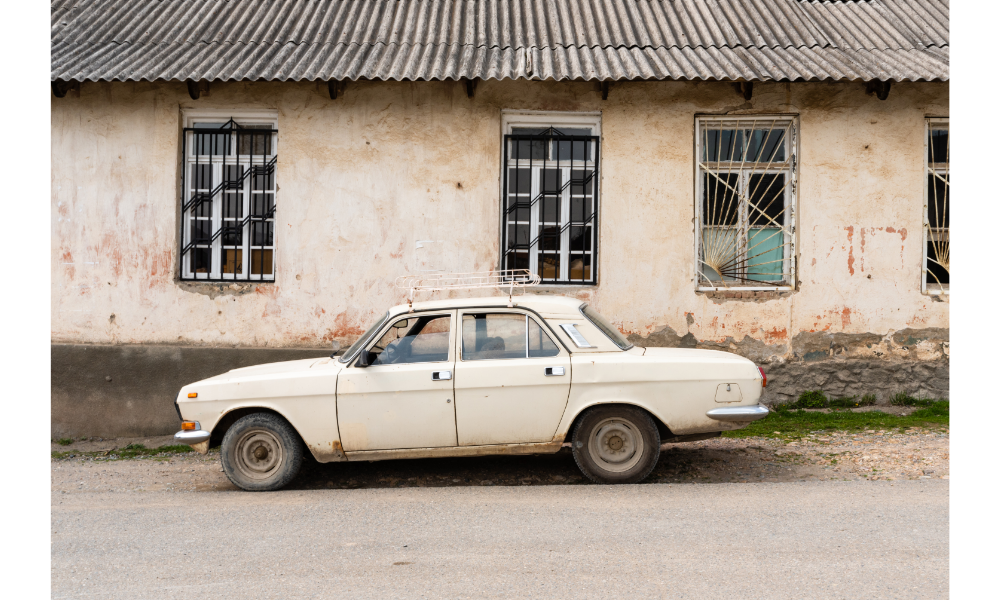 Carro branco antigo em frente a uma casa.