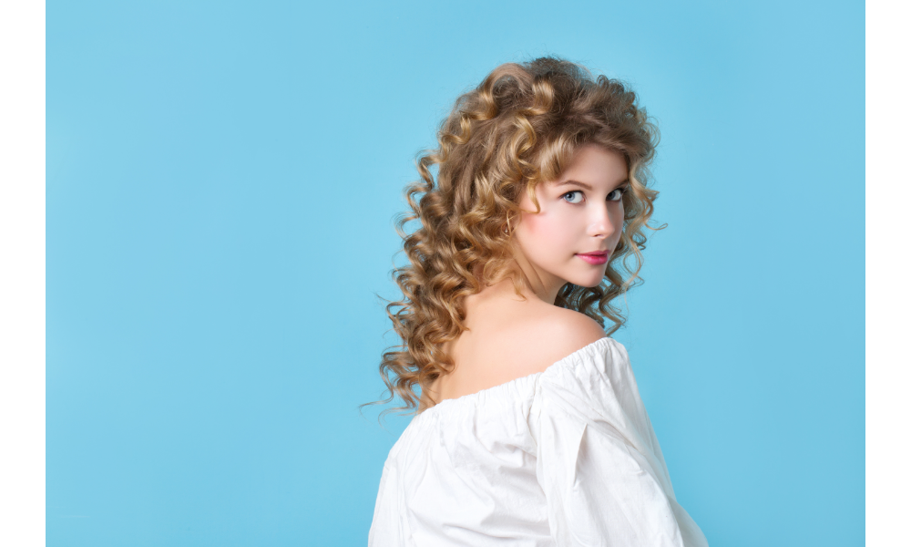 Mulher loira de cabelo cacheado em fundo azul.