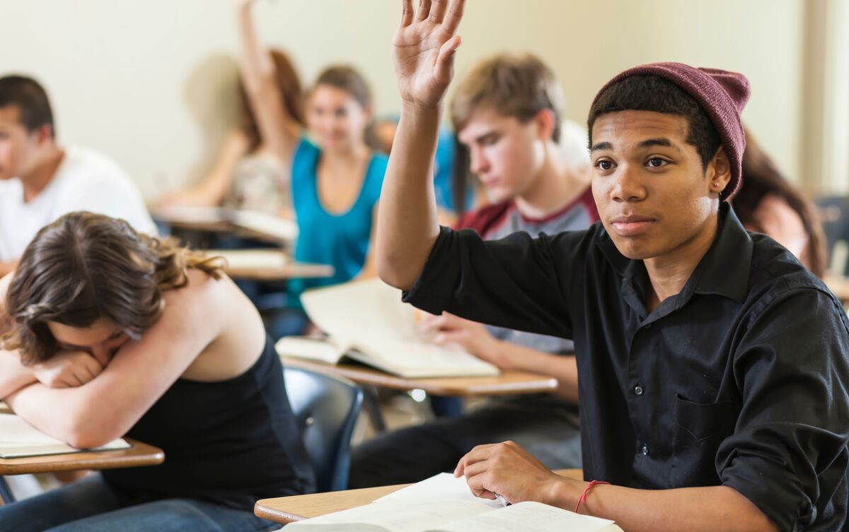 Alunos prestando atenção na aula e aluna dormindo.