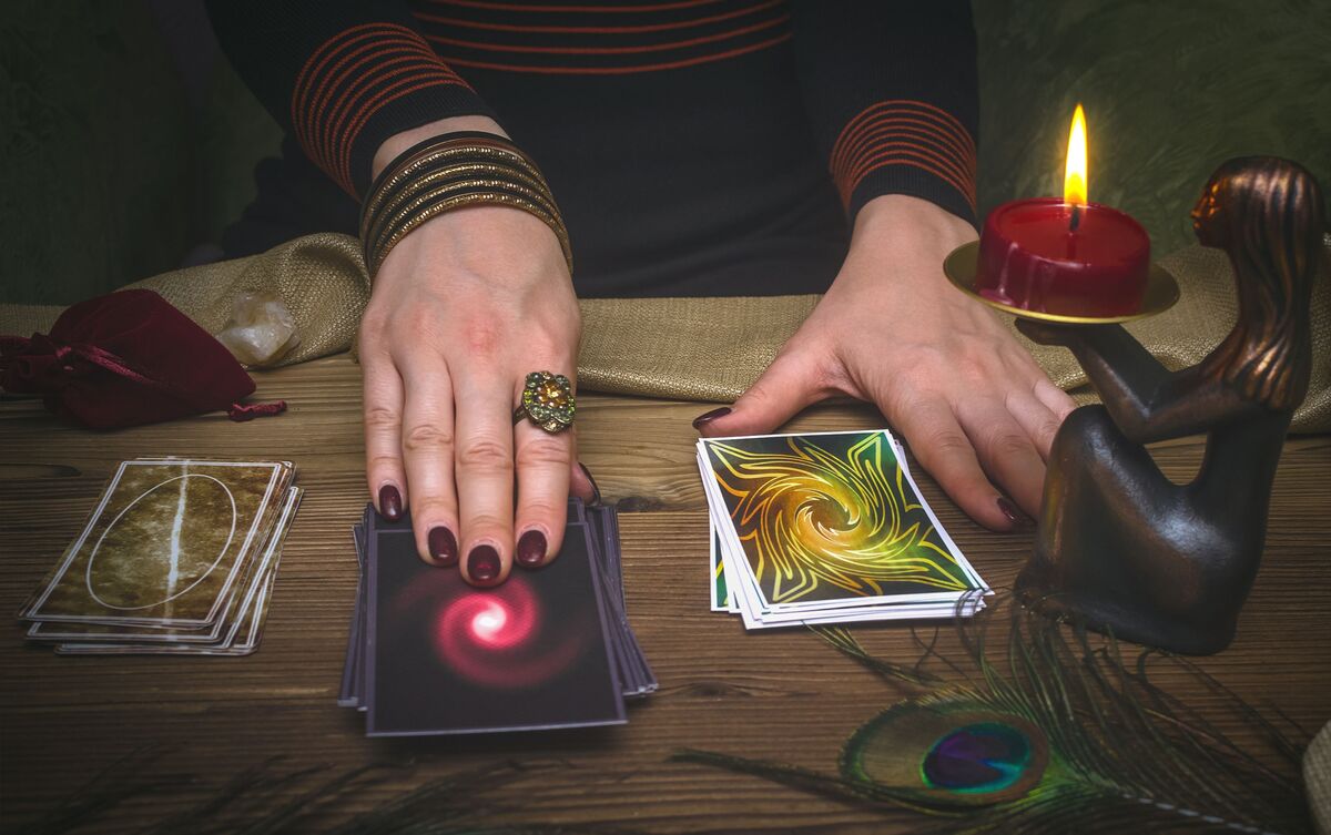 Mulher fazendo tiragem de cartas de Tarot em mesa.