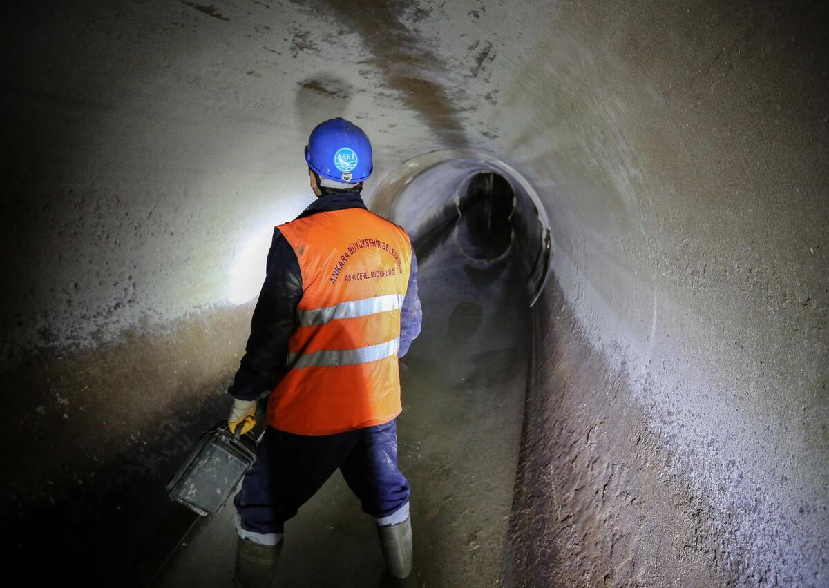 Homem dentro do túnel de esgoto.