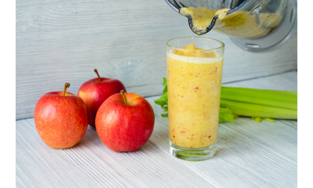 Copo com suco, ao lado de maçãs.