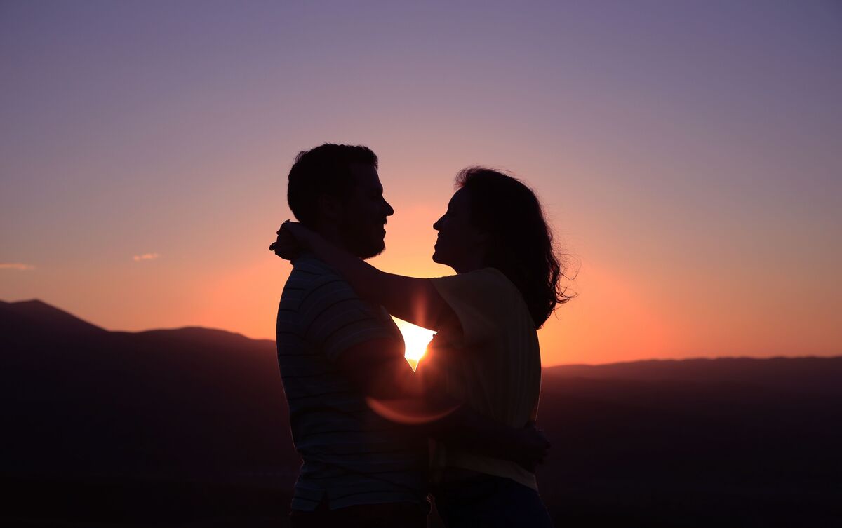 Casal abraçado ao pôr do sol.