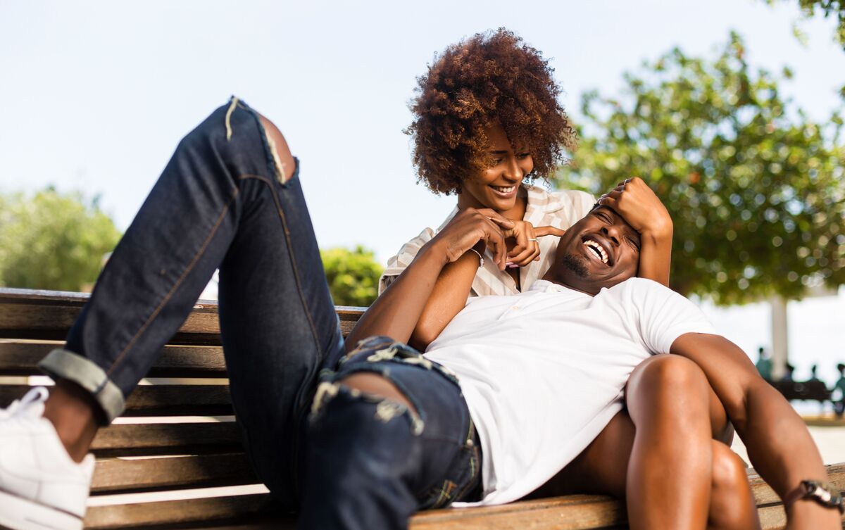 Casal feliz sentado em banco de parque.