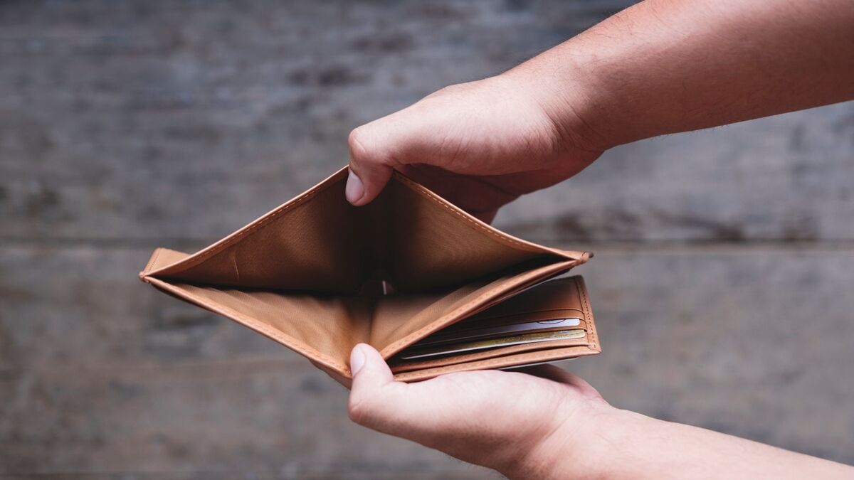 Mãos segurando uma carteira sem dinheiro.