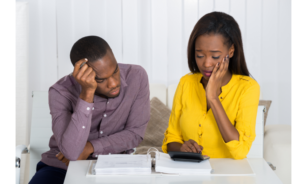 Casal preocupado com as finanças com um caderno e calculadora.